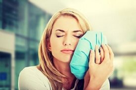 woman holding ice pack to face in pain emergency dentist Greenbelt, MD
